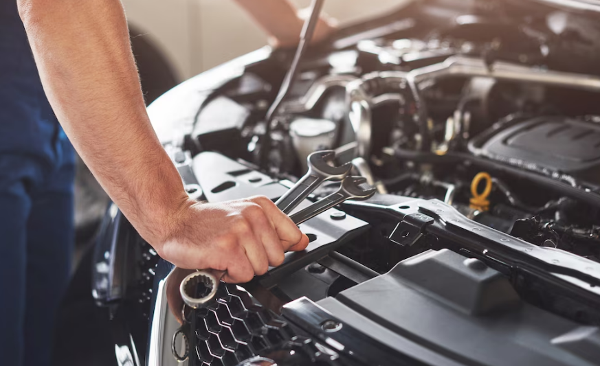 Mechanic working under the hood of a car at a local autoshop